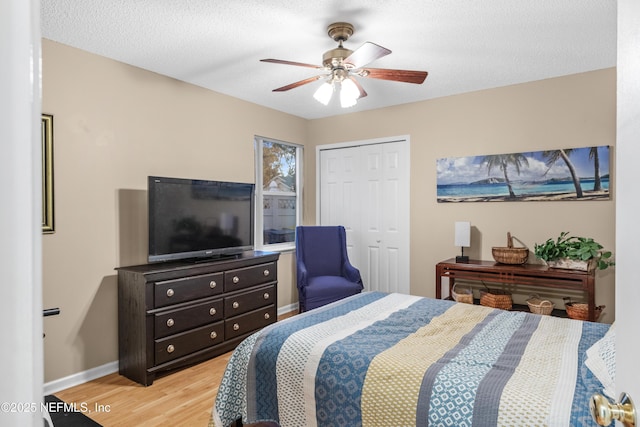 bedroom featuring ceiling fan, a textured ceiling, a closet, and light hardwood / wood-style flooring