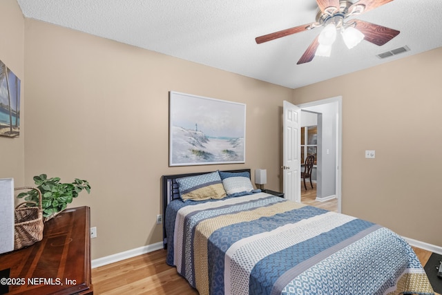 bedroom with ceiling fan, a textured ceiling, and light hardwood / wood-style flooring