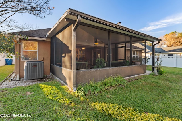 exterior space featuring ceiling fan, a sunroom, a lawn, and central air condition unit