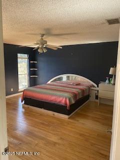 bedroom featuring ceiling fan, wood-type flooring, and a textured ceiling