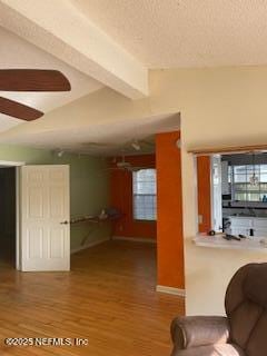 unfurnished living room featuring beam ceiling, hardwood / wood-style floors, and ceiling fan