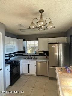 kitchen with stainless steel appliances, hanging light fixtures, tile countertops, and white cabinets