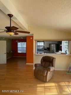 unfurnished living room featuring ceiling fan, wood-type flooring, vaulted ceiling, and a textured ceiling