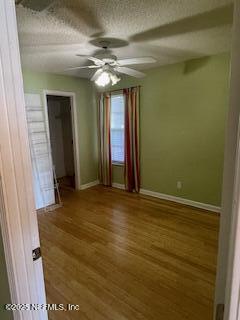 empty room featuring ceiling fan, hardwood / wood-style floors, and a textured ceiling