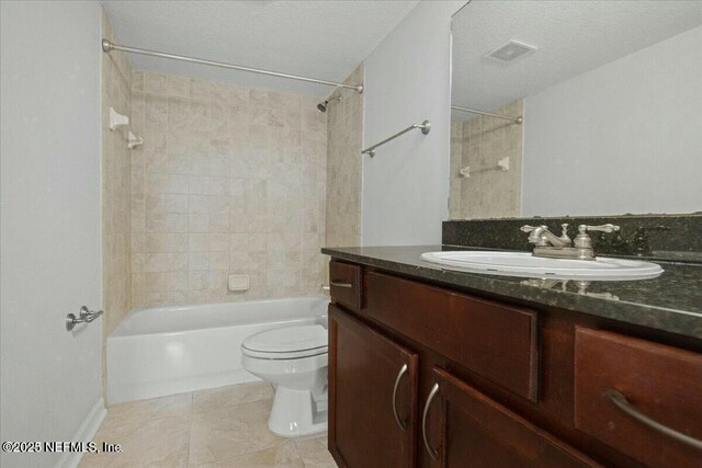 full bathroom featuring toilet, vanity, tile patterned flooring, tiled shower / bath combo, and a textured ceiling