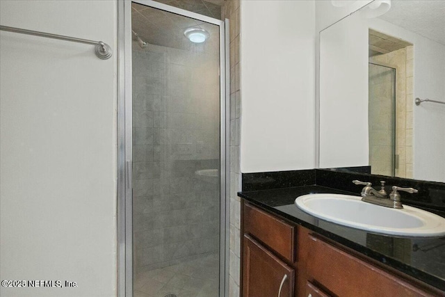 bathroom featuring a shower with door and vanity