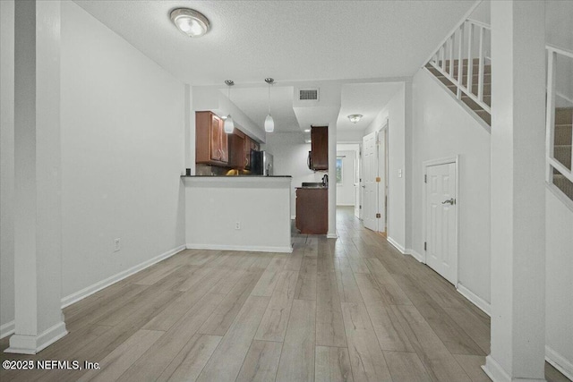 unfurnished living room with light wood-type flooring and a textured ceiling