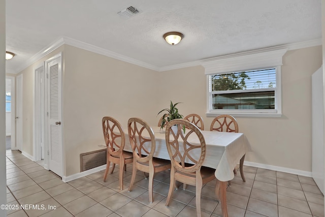 tiled dining room with a textured ceiling and ornamental molding