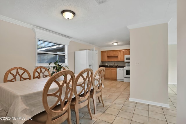 tiled dining area with sink, ornamental molding, and a textured ceiling