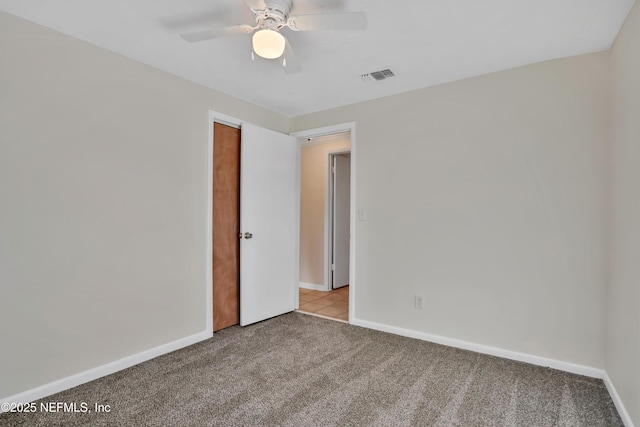 empty room featuring ceiling fan and light carpet