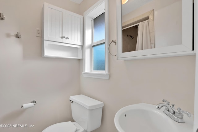 bathroom with toilet, walk in shower, and sink