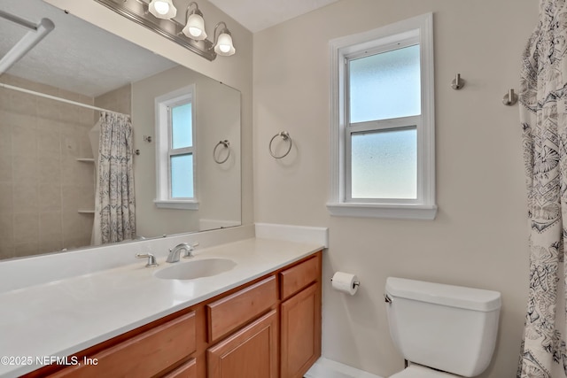 bathroom featuring a wealth of natural light, toilet, vanity, and walk in shower