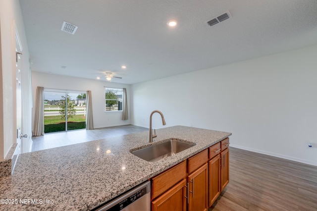 kitchen with sink, light hardwood / wood-style flooring, ceiling fan, light stone counters, and stainless steel dishwasher