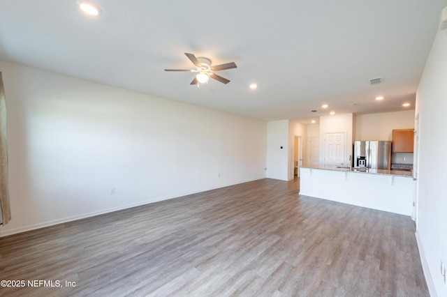 unfurnished living room featuring ceiling fan and light hardwood / wood-style flooring