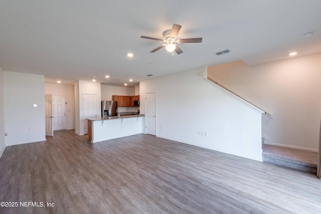 unfurnished living room featuring ceiling fan and light wood-type flooring