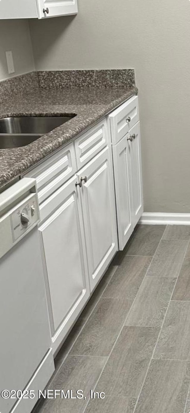 kitchen with white cabinetry, dark stone countertops, and dishwasher