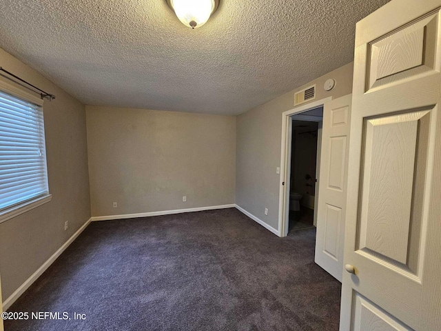 carpeted empty room featuring a textured ceiling