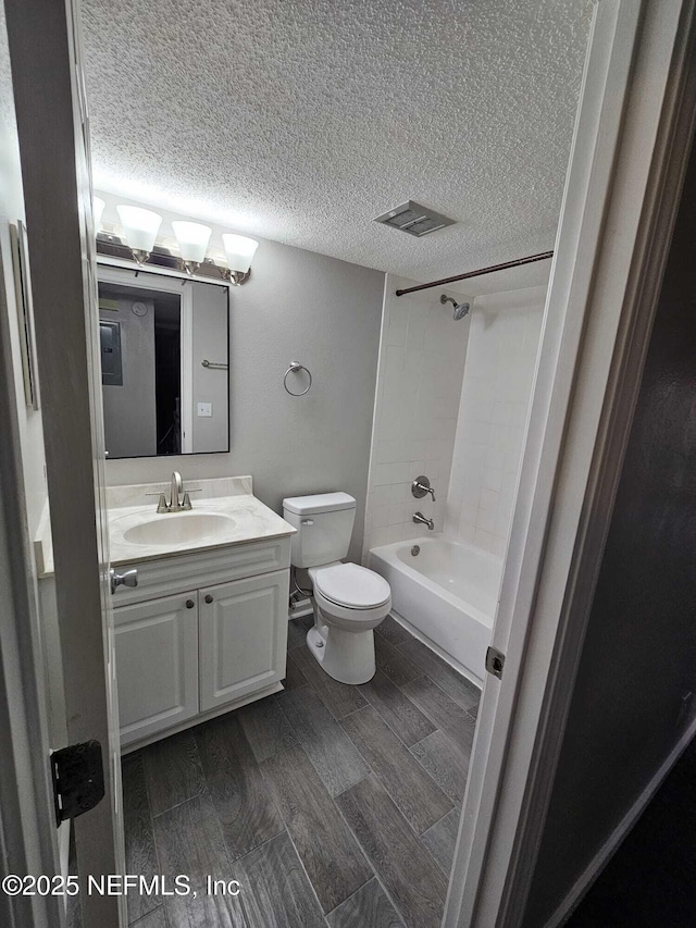 full bathroom featuring toilet, tiled shower / bath combo, vanity, and a textured ceiling