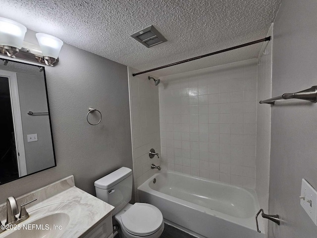 full bathroom with toilet, vanity, a textured ceiling, and tiled shower / bath