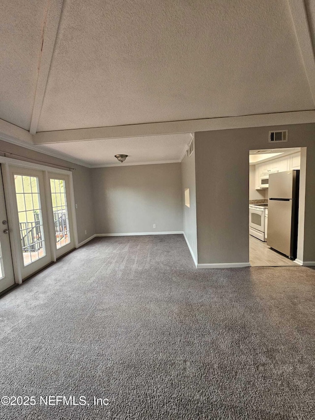 unfurnished living room featuring carpet, beamed ceiling, and a textured ceiling