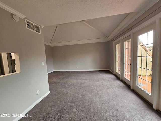 carpeted empty room featuring a textured ceiling, ornamental molding, and vaulted ceiling