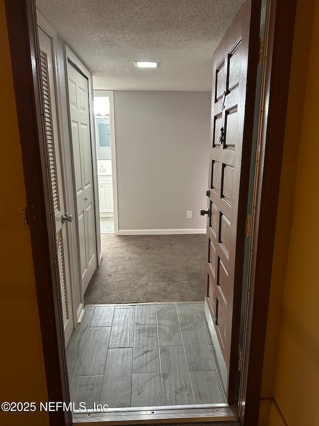 hallway featuring a textured ceiling and light carpet