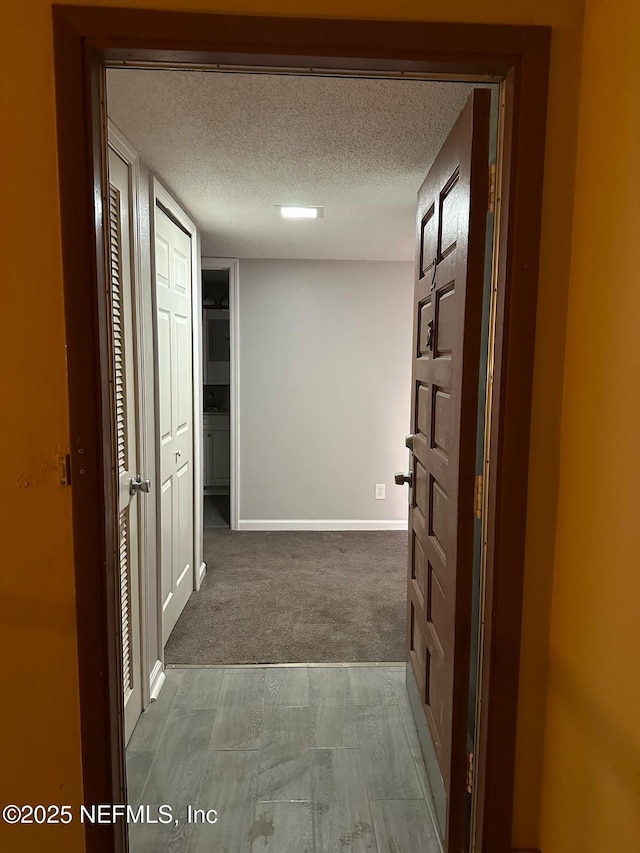 hallway with carpet floors and a textured ceiling