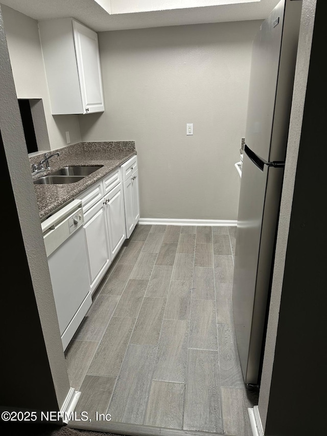 kitchen with dishwasher, white cabinets, stainless steel refrigerator, and sink