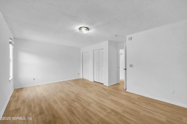 empty room with a textured ceiling and light wood-type flooring