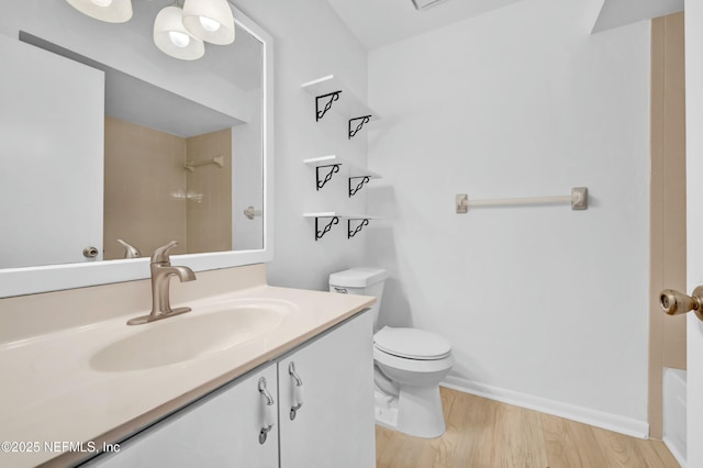 bathroom with toilet, hardwood / wood-style floors, and vanity