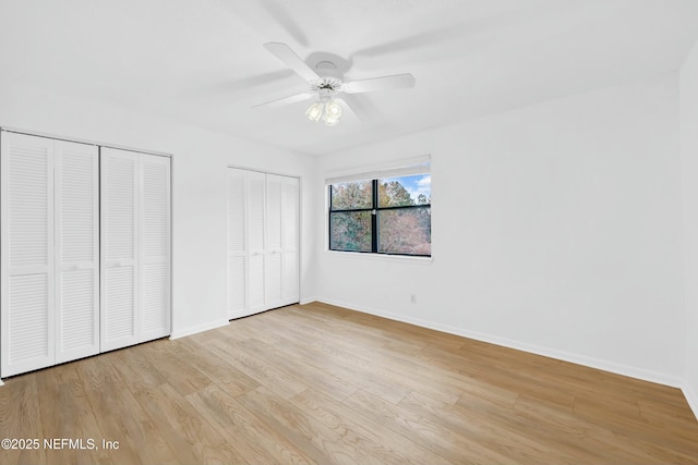 unfurnished bedroom featuring ceiling fan, multiple closets, and light hardwood / wood-style floors