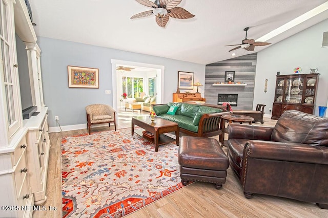 living room with ceiling fan, light hardwood / wood-style flooring, lofted ceiling, and a fireplace