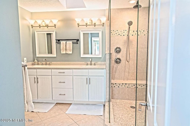 bathroom with tile patterned flooring, a shower with door, a textured ceiling, and vanity