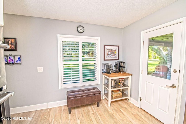 doorway with light hardwood / wood-style floors and a textured ceiling