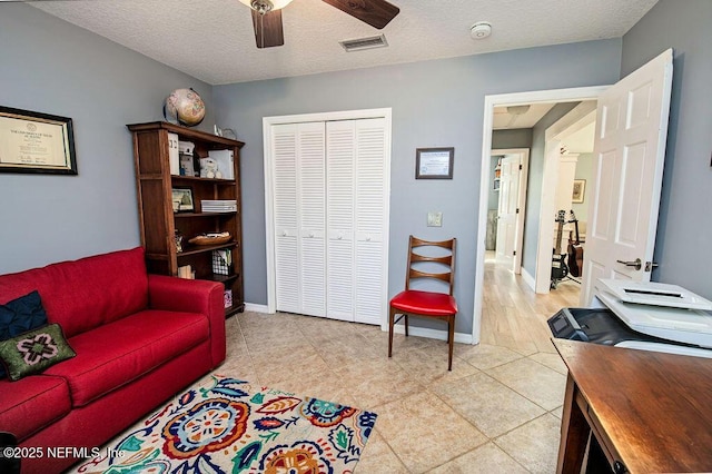 tiled living room featuring ceiling fan and a textured ceiling