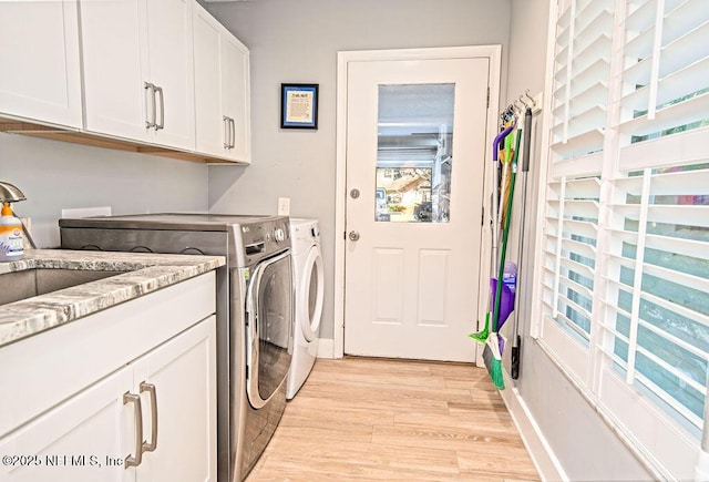 laundry area featuring plenty of natural light, cabinets, light hardwood / wood-style flooring, and washer and clothes dryer