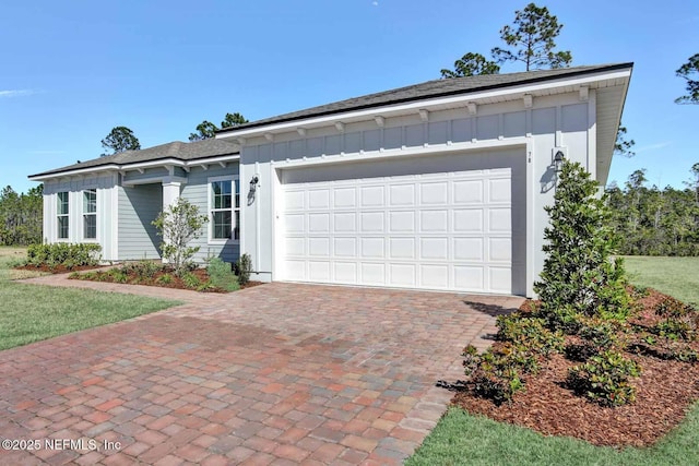 ranch-style home featuring decorative driveway, board and batten siding, and an attached garage