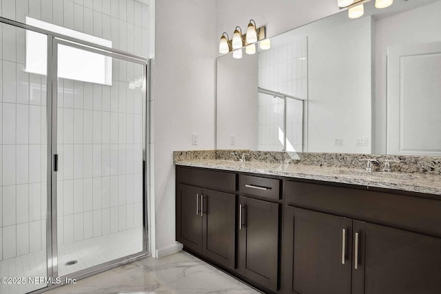 full bathroom featuring a shower stall, double vanity, marble finish floor, and a sink