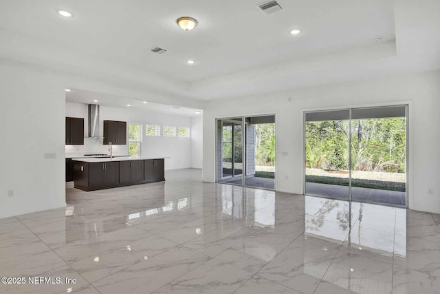 unfurnished living room with recessed lighting, visible vents, marble finish floor, and a tray ceiling