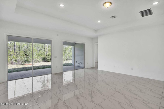 spare room with recessed lighting, visible vents, and a raised ceiling