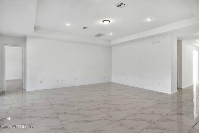 spare room with recessed lighting, visible vents, a raised ceiling, and marble finish floor