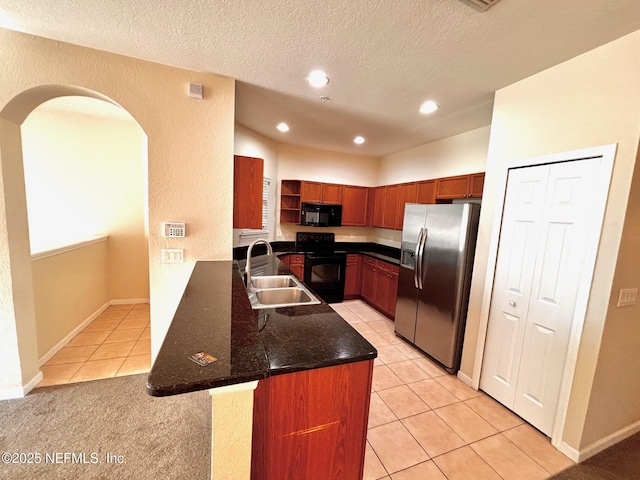 kitchen with kitchen peninsula, light tile patterned flooring, dark stone counters, black appliances, and sink