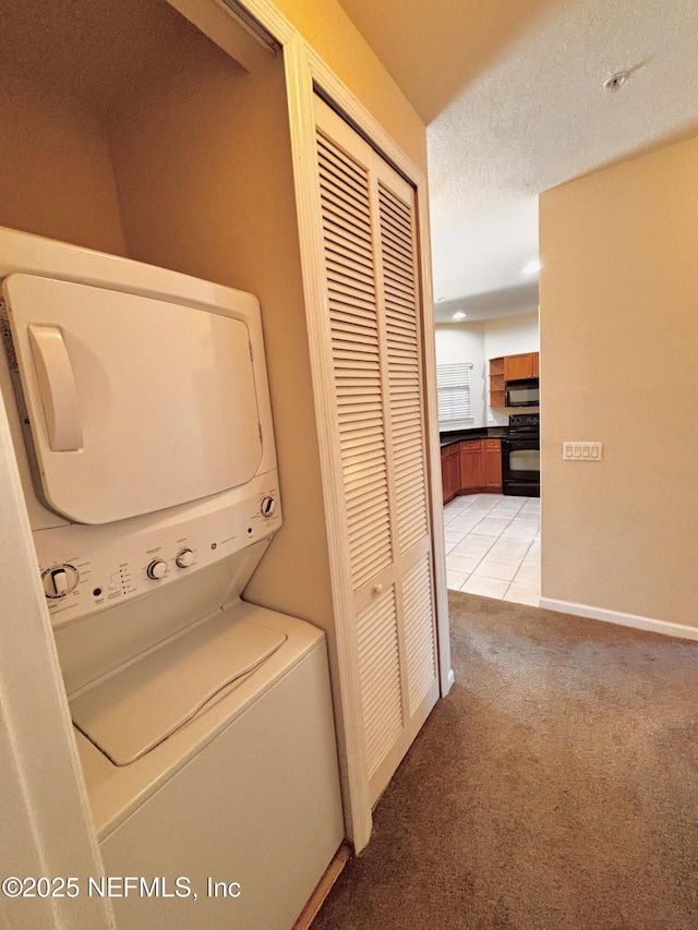 clothes washing area with stacked washing maching and dryer, a textured ceiling, and light colored carpet