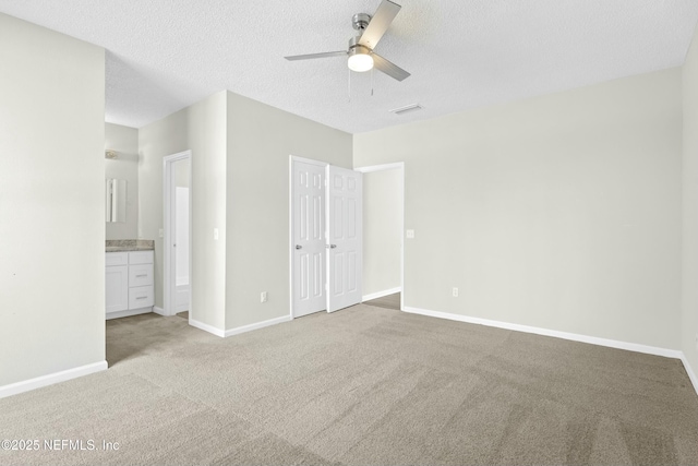 unfurnished bedroom with ceiling fan, light colored carpet, ensuite bath, a textured ceiling, and a closet