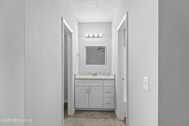 hallway with sink, a textured ceiling, and light carpet