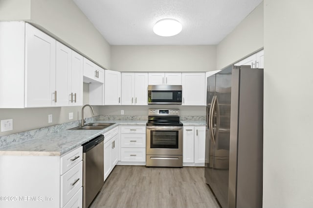 kitchen featuring a textured ceiling, stainless steel appliances, white cabinets, and sink