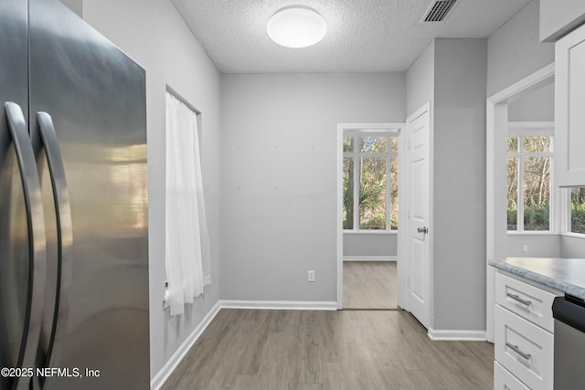 kitchen with light hardwood / wood-style floors, a wealth of natural light, white cabinets, and stainless steel appliances