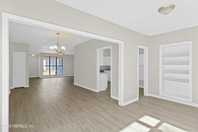 unfurnished living room with an inviting chandelier, light hardwood / wood-style floors, and built in shelves