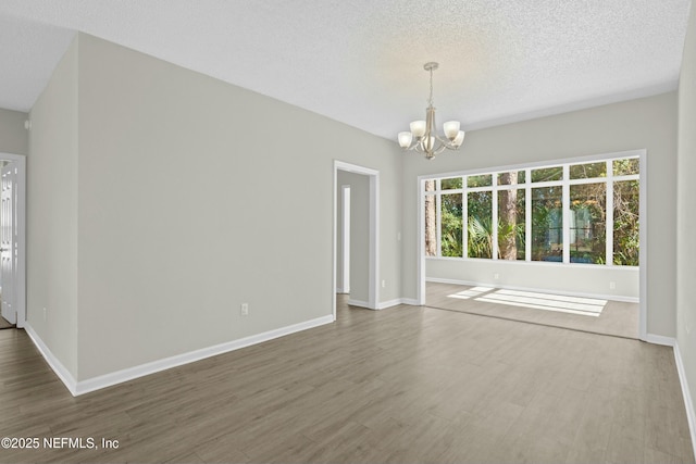 spare room featuring a notable chandelier and hardwood / wood-style floors