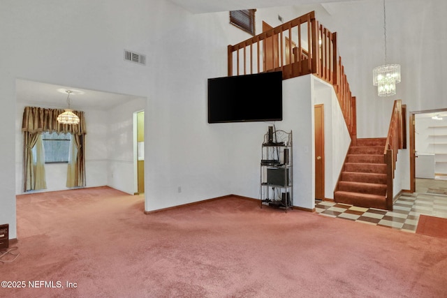 unfurnished living room featuring a towering ceiling, a chandelier, and carpet flooring